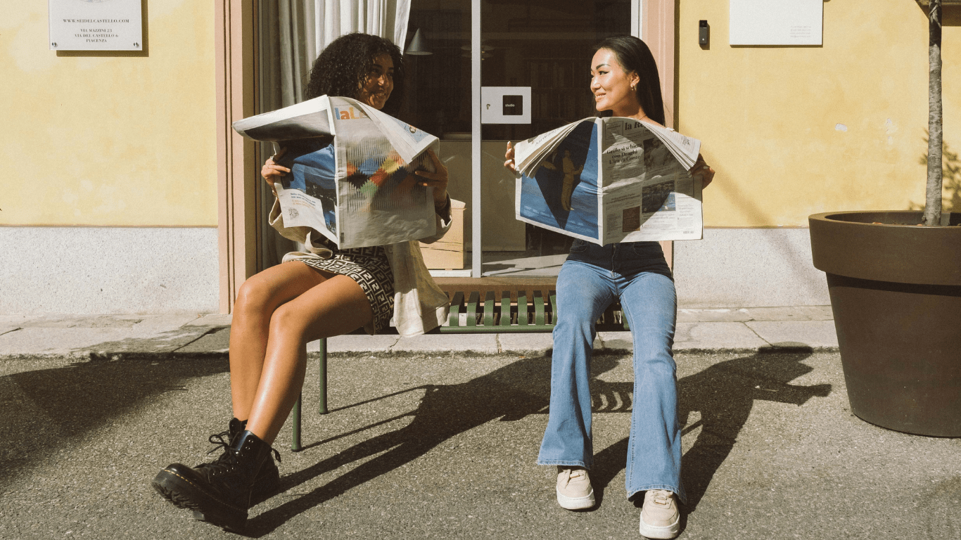 Best friends holding newspaper